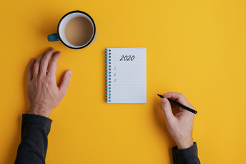 Top view of a man writing down plans or resolutions for the year 2020