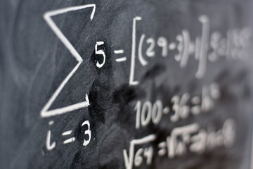 Operacion matematica escrita con tiza en una pizarra, enfocando el numero cinco