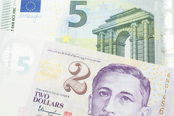 A close up image of a fve euro bank note from the European Central bank and the European Union in macro with a two dollar bill from Singapore