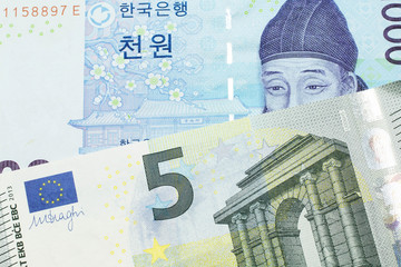 A blue two thousand won note from South Korea close up in macro with a five Euro note from the European Union eurozone