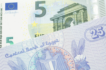 A close up image of a purple, twenty five Egyptian piastres note close up in macro with a blue and green, European five euro bank note