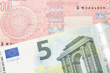 A red ten taka note from Bangladesh, close up in macro with a five Euro note