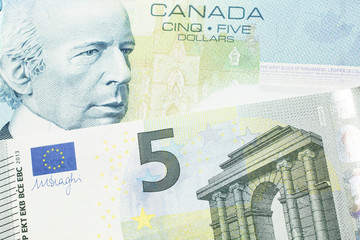 A close up macro shot of a blue five Canadian dollar bill with a five Euro note