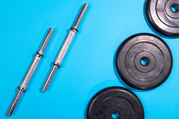 Obraz na płótnie Canvas Fitness or bodybuilding. Sports equipment on a blue background, barbell, dumbbell, top view