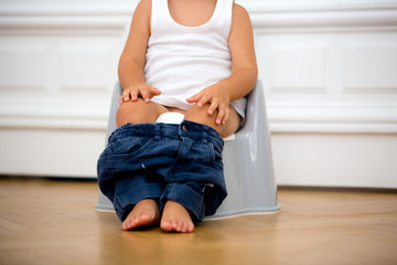 Infant child baby boy toddler sitting on potty, playing with toys in living room