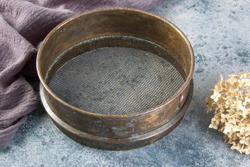 Antique brass  sieve on concrete background.