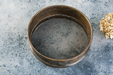 Antique brass  sieve on concrete background.