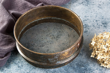 Antique brass  sieve on concrete background.