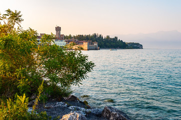 Fototapeta na wymiar Evening cityscape of Sirmione medieval city located on southern peninsula of Garda lake in Lombardy, Italy. Waterscape scene