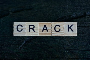 gray word crack from small wooden letters on a black table