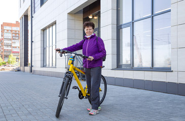 Portrait of happy adorable senior woman riding a bike in a city