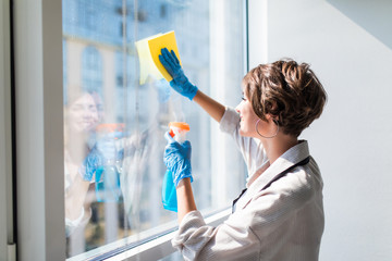 Young woman washing window. Housewife cleaning window at home. Housework