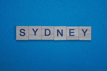 gray word sydney from small wooden letters on a blue table