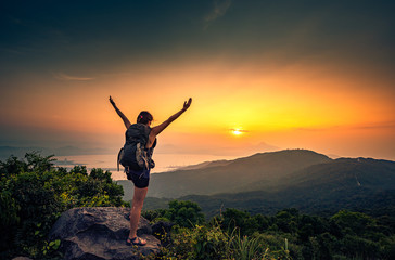 Young hiker standing with arms stretched on top of the Mountain Ban Co Peak, Da Nang Vietnam