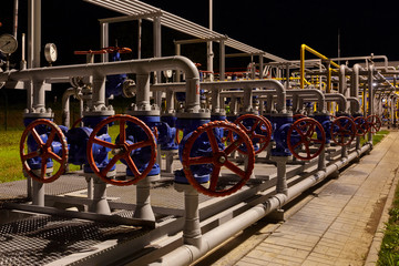 Pipeline system at a gas production and processing plant. Pipes, valves, manometers. Night shooting