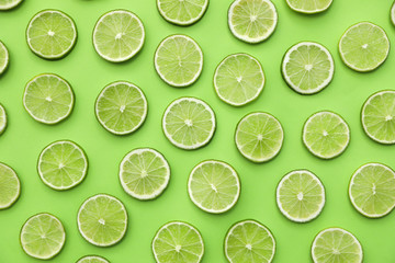 Slices of fresh juicy limes on green background, flat lay