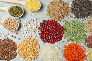 Different types of legumes and cereals on grey marble table, flat lay. Organic grains
