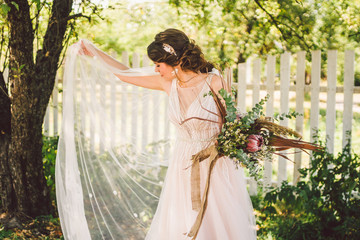 Beautiful bride with bouquet flowers stands on forest background. Rustic style. beautiful bride in...