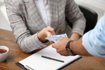 Man giving bribe money to woman at table, closeup