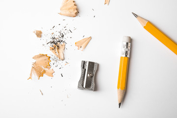 Graphite pencils, shavings and sharpener on white background, top view