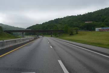 Open and clear highway road with a an upcoming bridge on a cloudy overcast spring day.