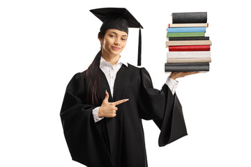 Female graduate in a gown with a pile of books and pointing
