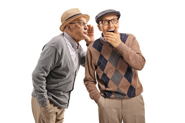 Elderly gentleman whispering a secret to another elderly man