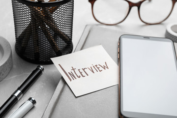 Reminder note about job interview and stationery on table, closeup