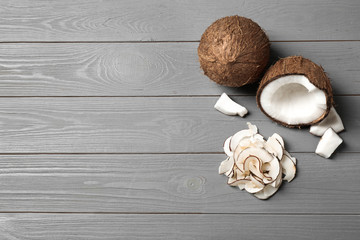 Flat lay composition with tasty coconut chips on grey wooden table. Space for text