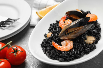 Delicious black risotto with seafood on table, closeup