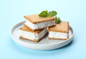 Sweet delicious ice cream cookie sandwiches on light blue background
