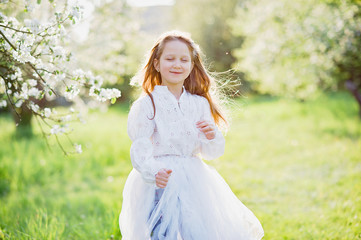 girl sniffing flowers of apple orchard. garden with flowering trees.