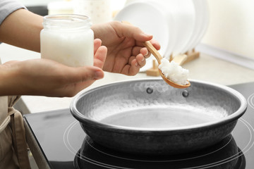 Woman cooking with coconut oil on induction stove, closeup