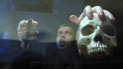 view through a glass countertop. the magician casts a spell . hand on its skull