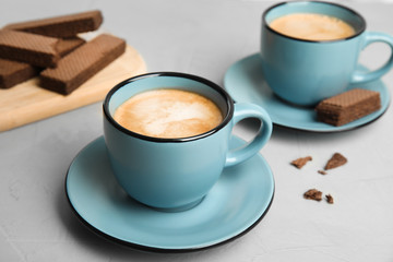 Delicious coffee and wafers for breakfast on grey table