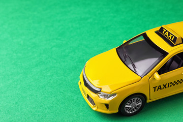 Yellow taxi car model on green background. Space for text