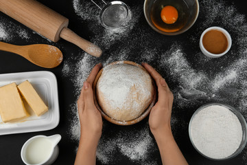 Woman with fresh dough at black table, top view. Baking pie
