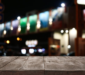 Empty wooden surface and blurred view of night city. Bokeh effect