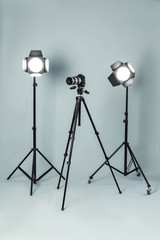 Professional video camera and lighting equipment on grey background