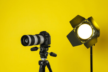 Professional video camera and lighting equipment on yellow background