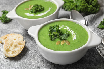 Tasty kale soup with pumpkin seeds on grey table