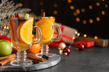 Aromatic white mulled wine on grey table against blurred lights. Space for text