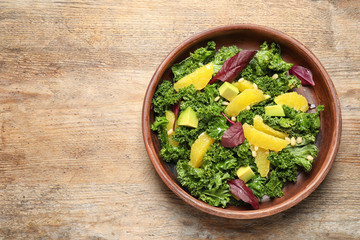 Tasty fresh kale salad on wooden table, top view. Space for text