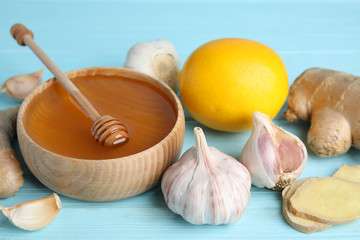 Fresh garlic and other natural cold remedies on light blue wooden table