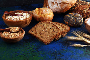 Assortment of baked bread and bread rolls and cutted bread on table background