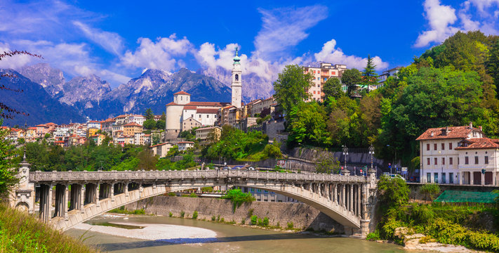 Belluno historic bridge and Piave river with old town in Dolomites mountains Italy. High resolution wide panorama for World Print of Veneto Alps. Ancient architecture and scenic mountain landscape