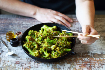 Broccoli cooked in a pan. Healthly food. A man with chopsticks eats broccoli.