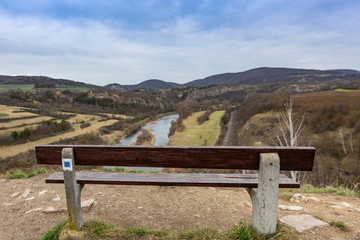 Bench on Tetín hillfort above the Berounka river near the town of Beroun in the Central Bohemian region. The bench has a blurred winter landscape without snow as a background.