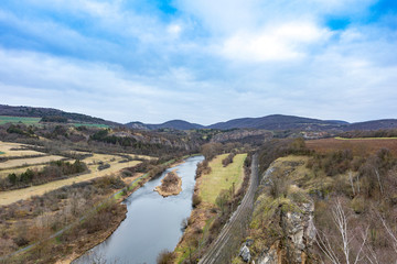 Fototapeta na wymiar Viewpoint from the Tetín hillfort above the Berounka river near the town of Beroun in the Central Bohemian Region. River Berounka with winter landscape without snow.