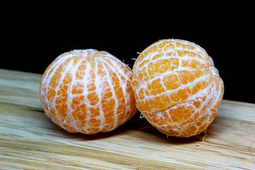 Tangerines on a wooden board with a black background.